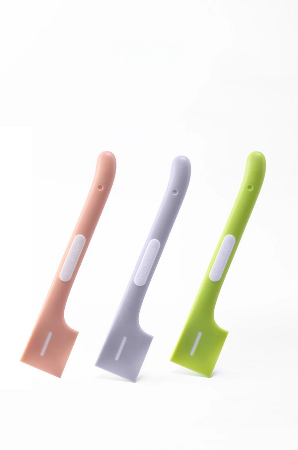 Three silicone spoons in pink, gray, and green on a white background