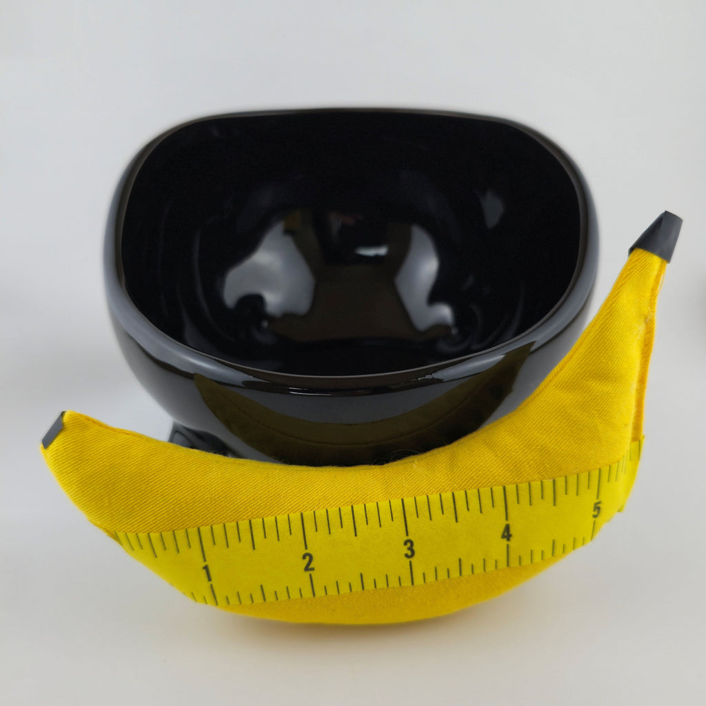 Black bowl with a yellow measuring tape around it on a white background
