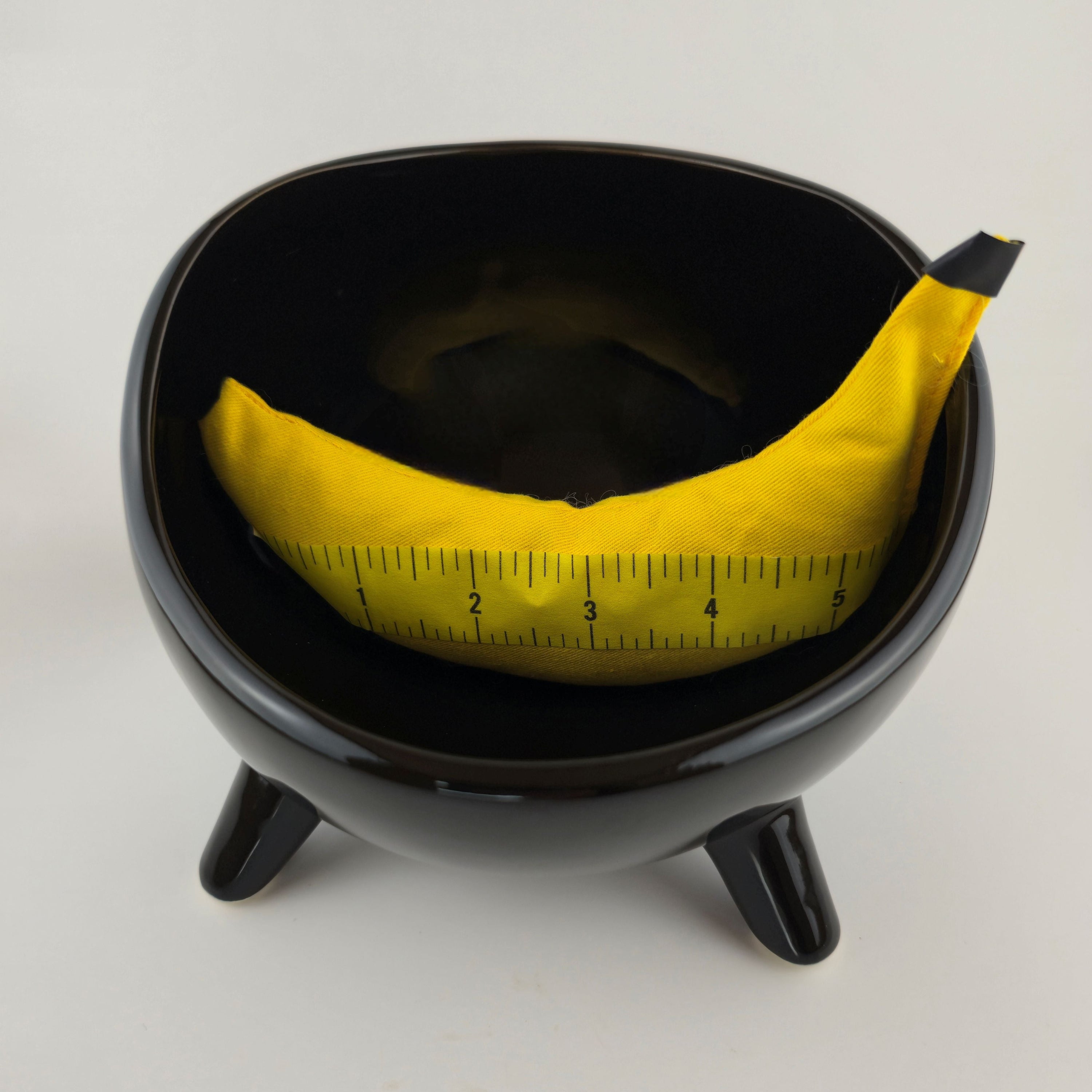 Black bowl with a yellow measuring tape inside on a white background