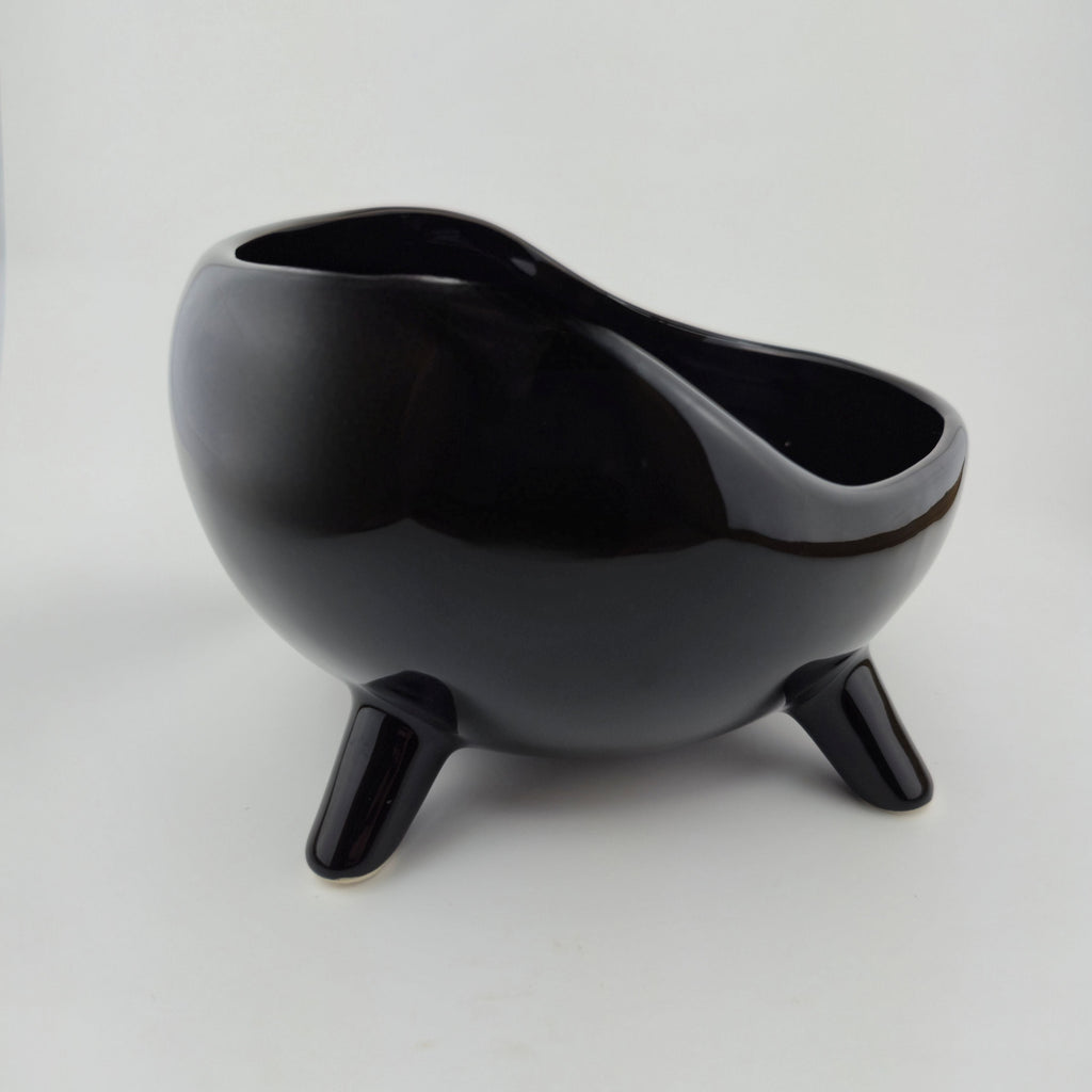 Black ceramic bowl with three legs on a white background