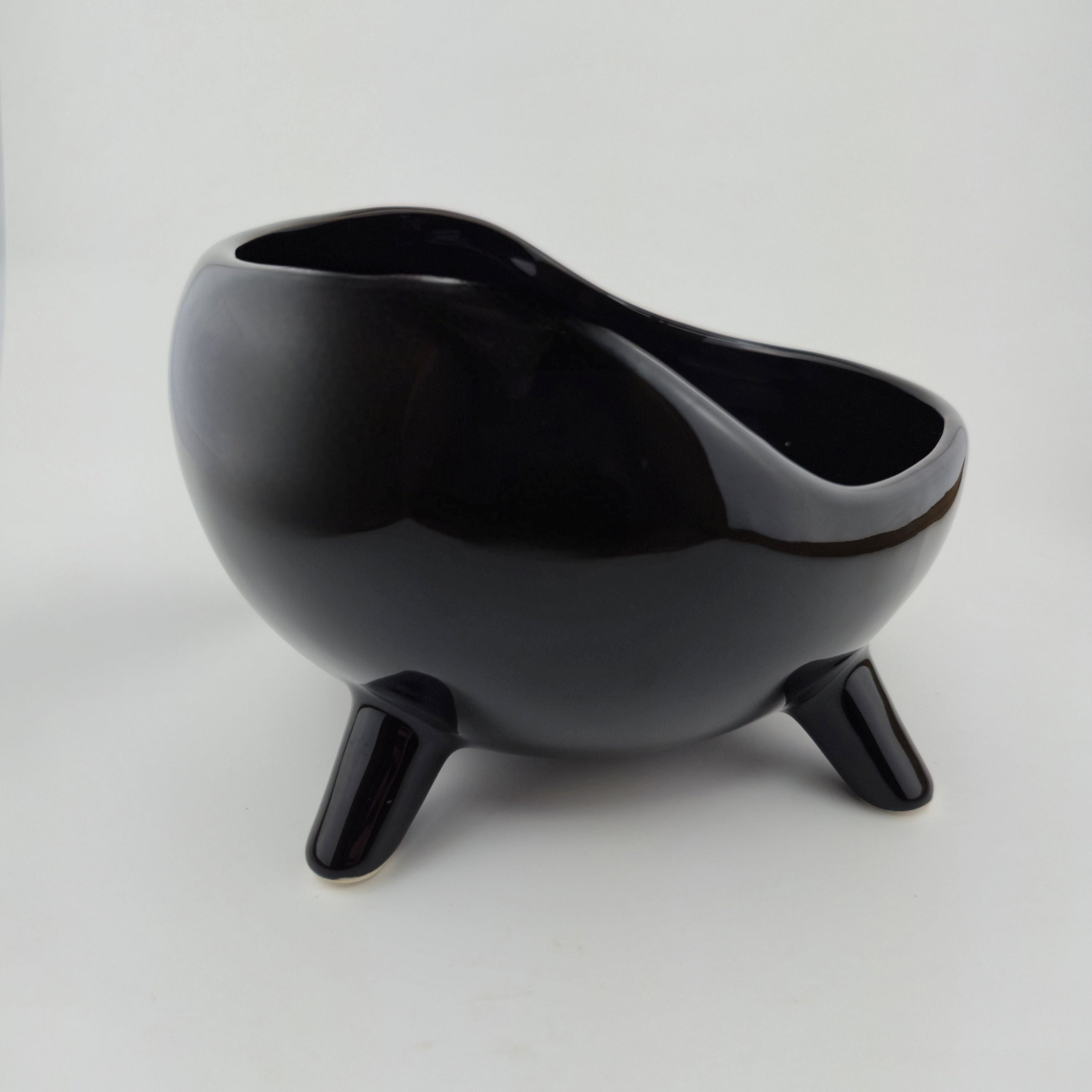 Black ceramic bowl with three legs on a white background
