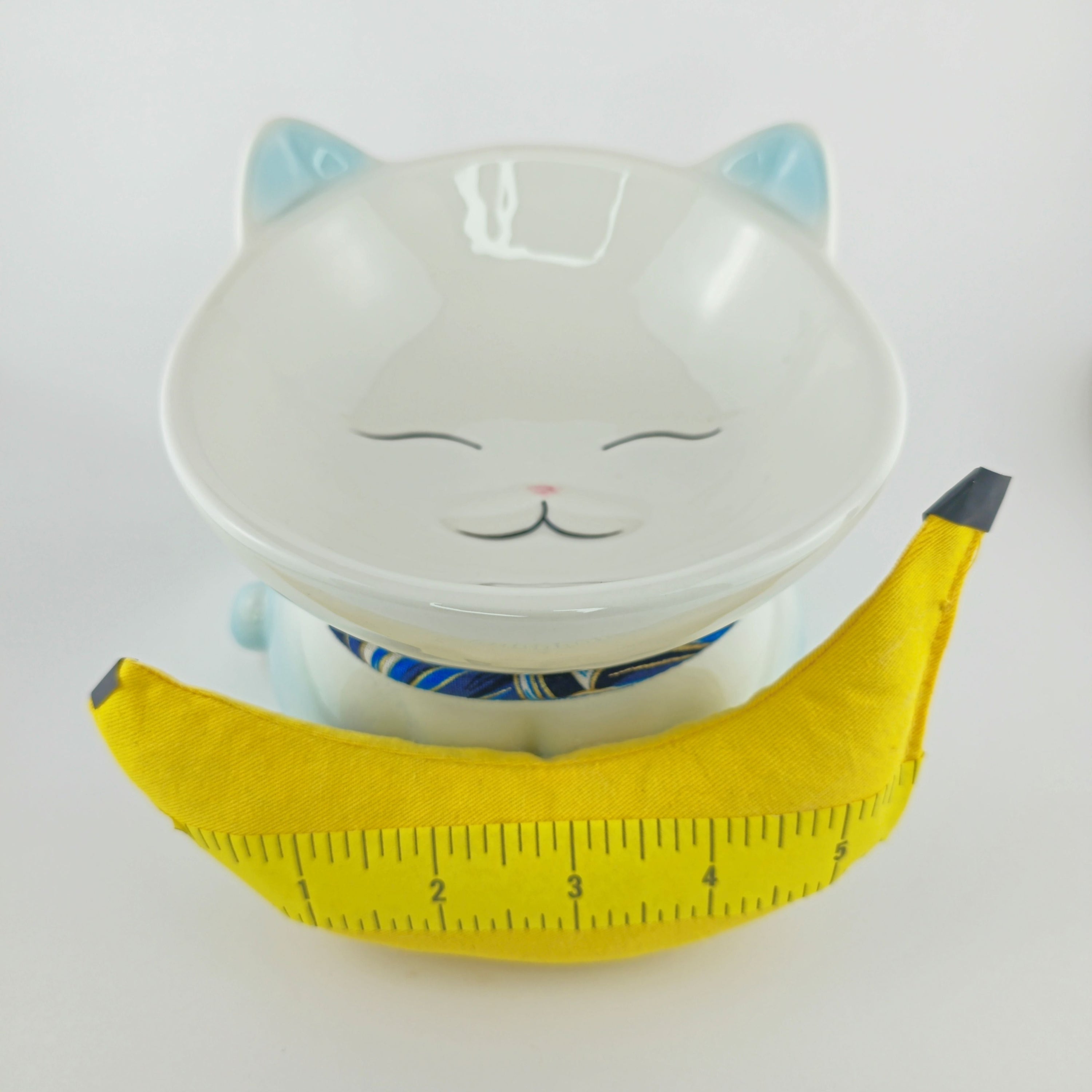 Cat-shaped bowl with a yellow measuring tape on a white background