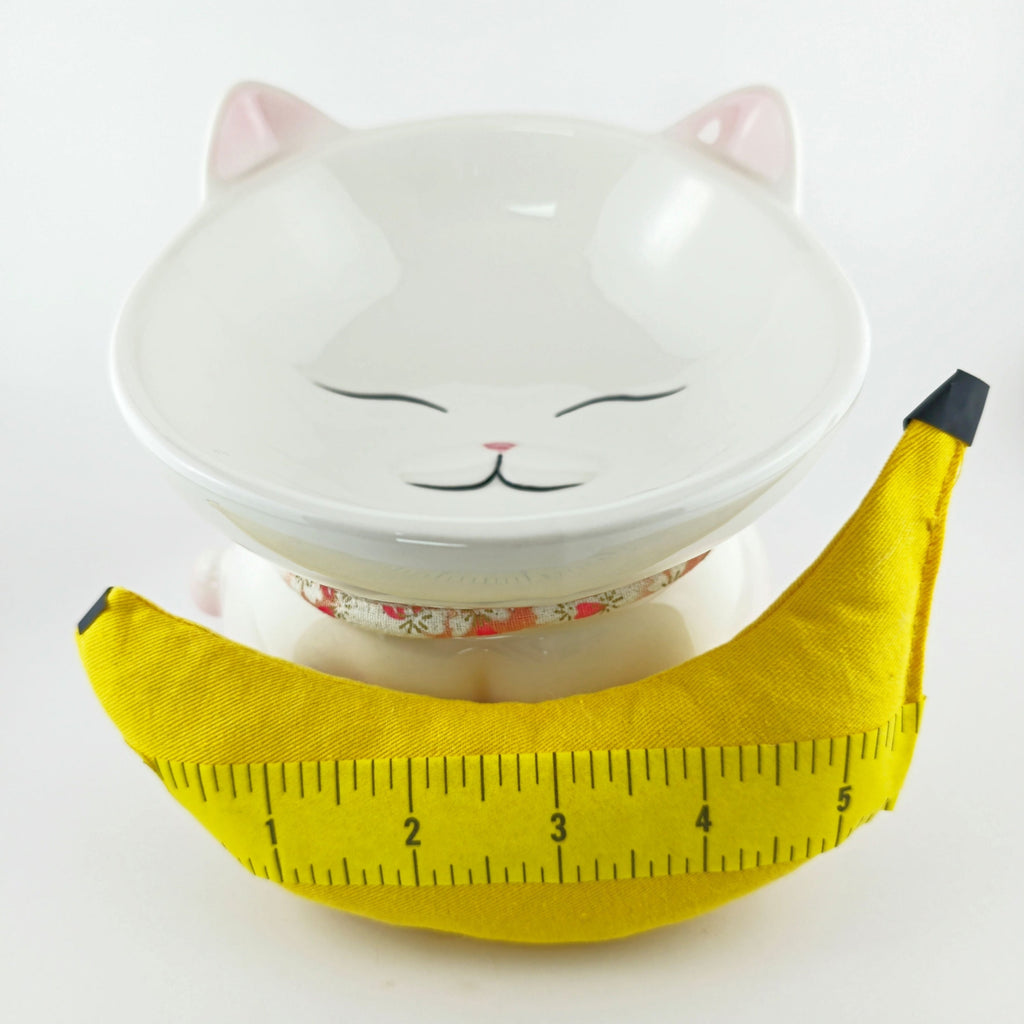 Cat-shaped bowl with a yellow banana-shaped product on a white background