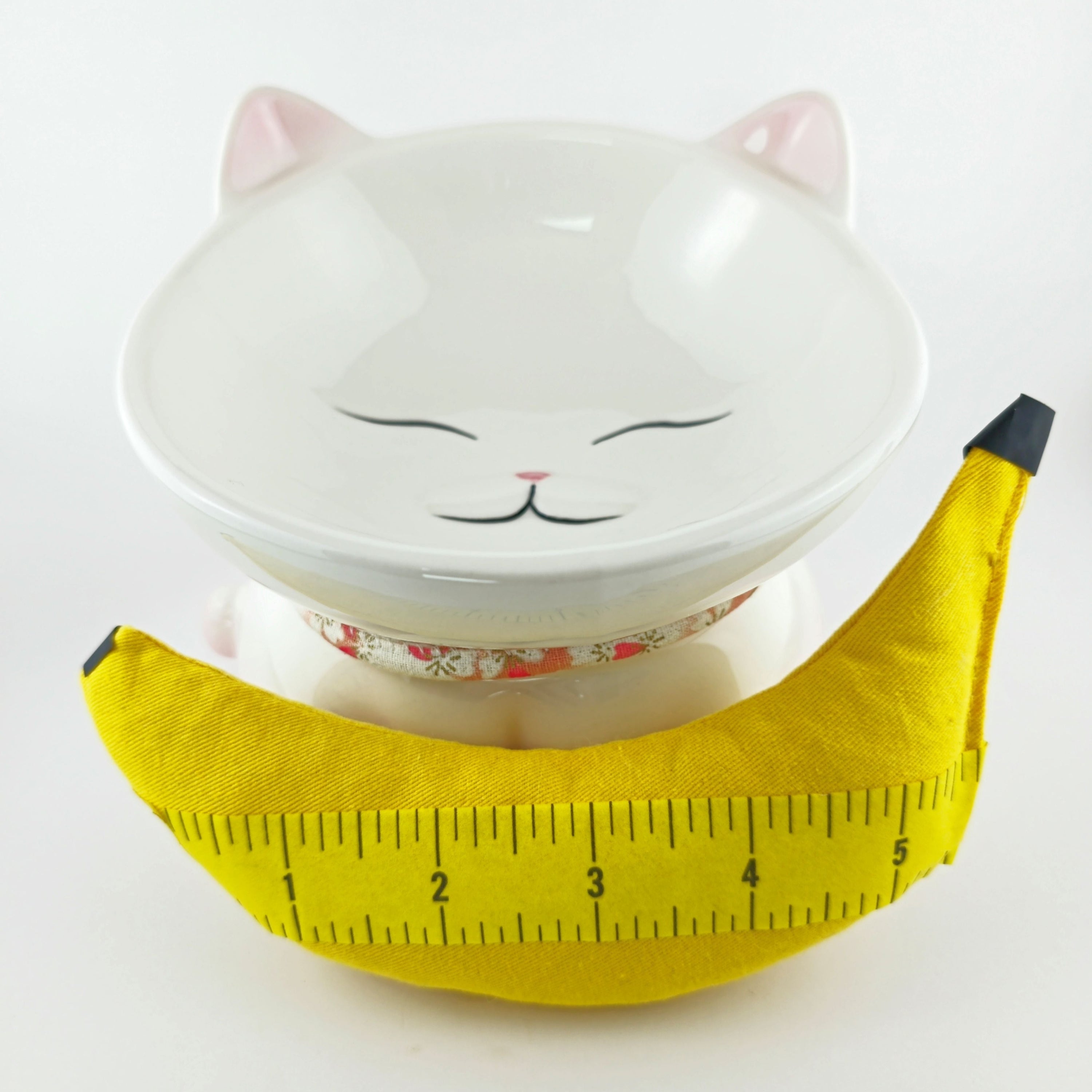 Cat-shaped bowl with a yellow banana-shaped product on a white background