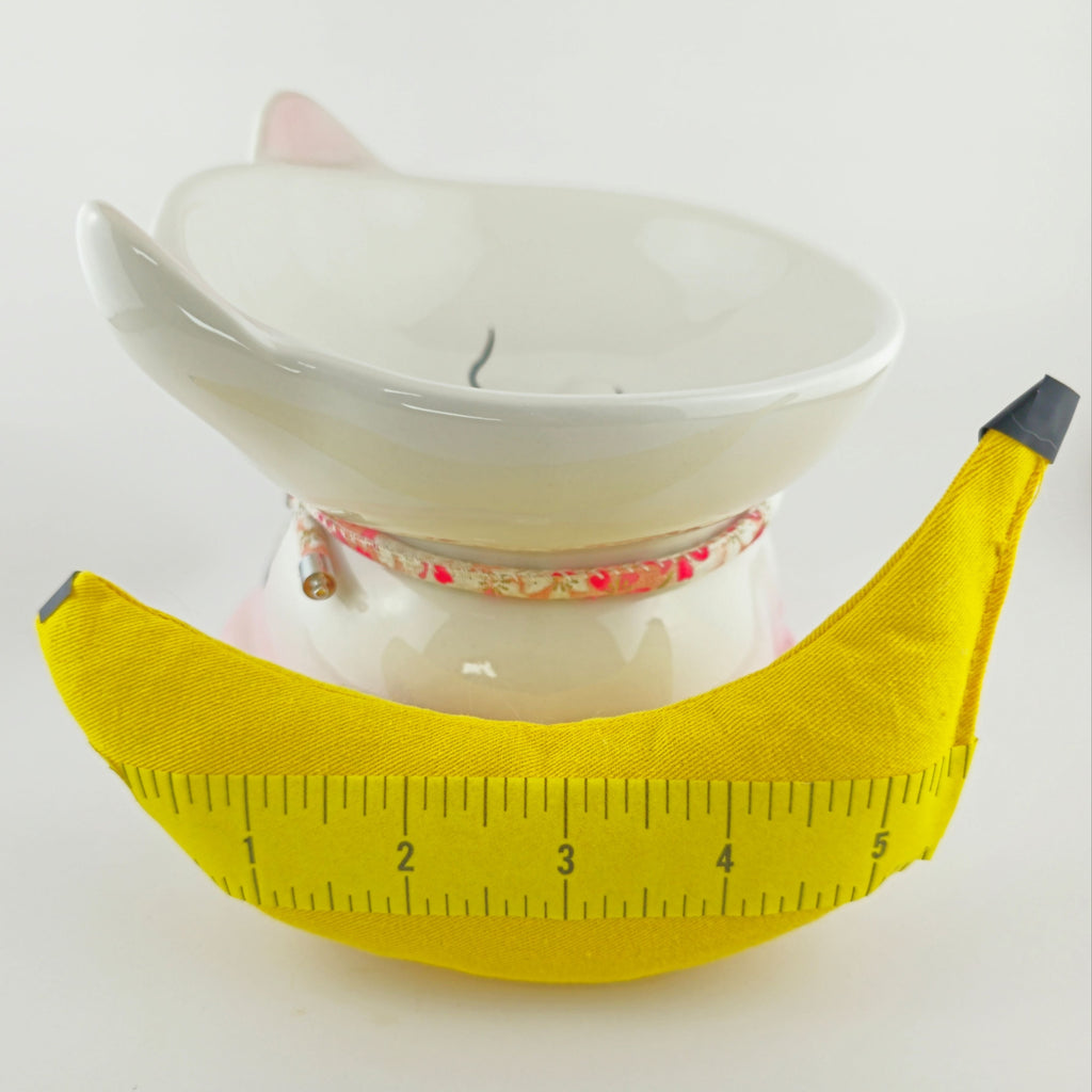 White ceramic bowl with a yellow banana-shaped object on a white background