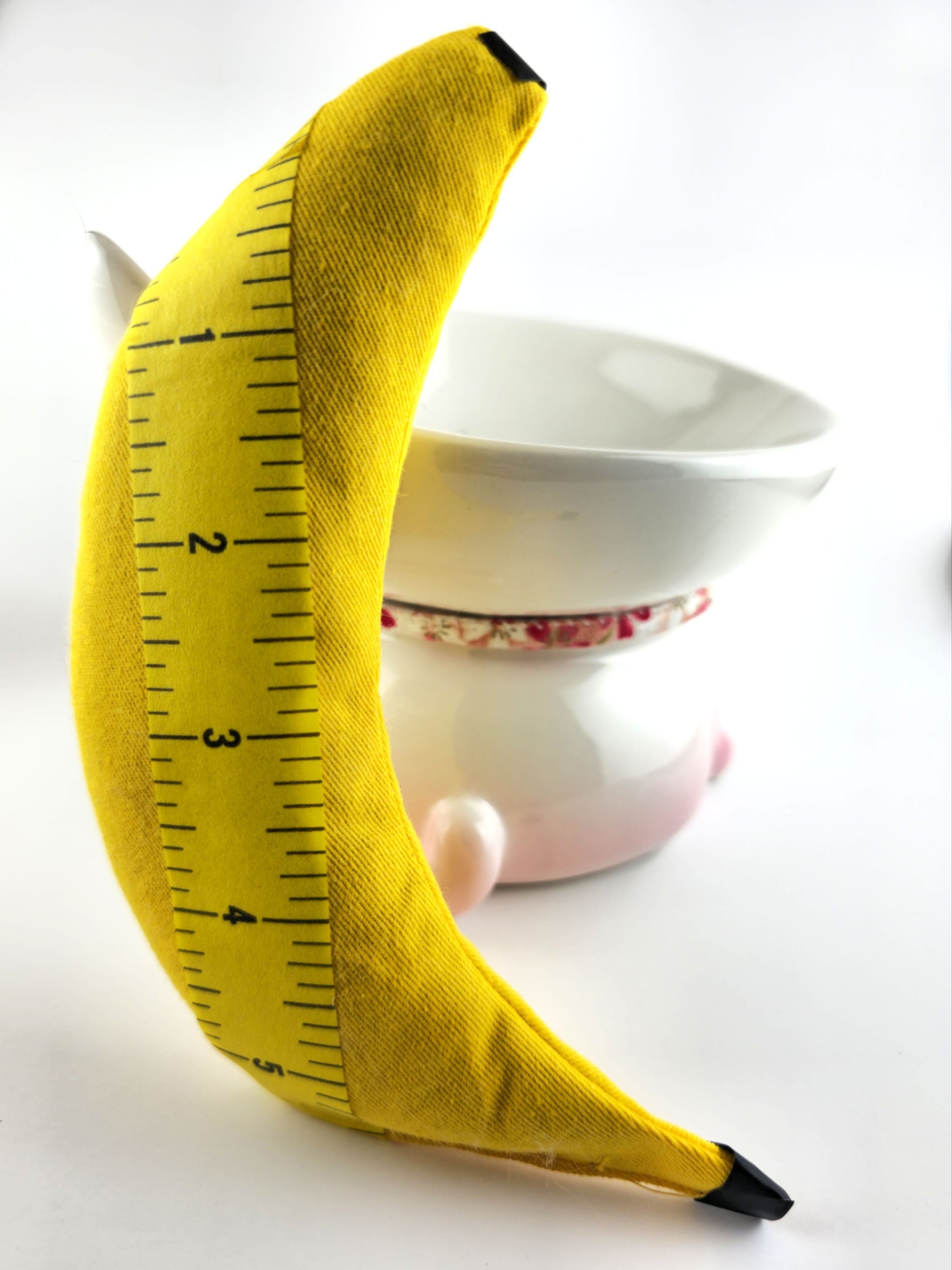 Yellow banana-shaped ruler with measurements on a white background