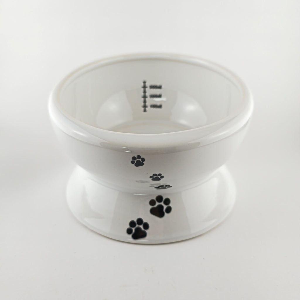 White pet bowl with black paw prints on a white background