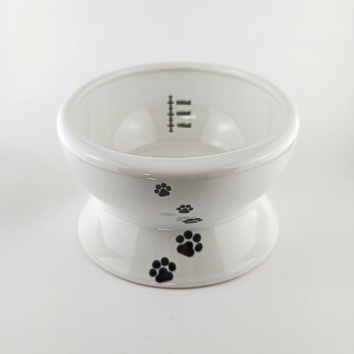 White pet bowl with black paw prints on a white background