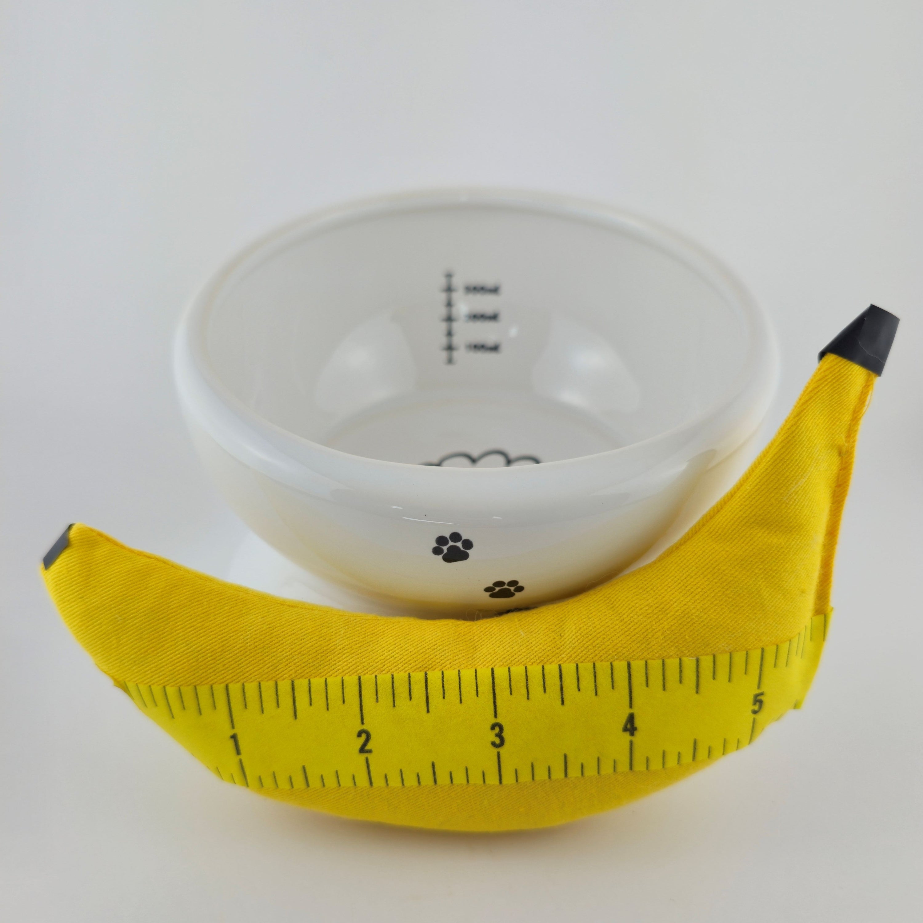Yellow banana with a measuring tape wrapped around it on a white background
